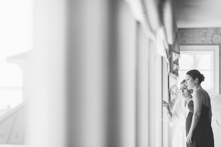 Bride and her sister look out of the window on the morning of her Mallard Island Yacht Club wedding. Captured by NJ wedding photographer Ben Lau.