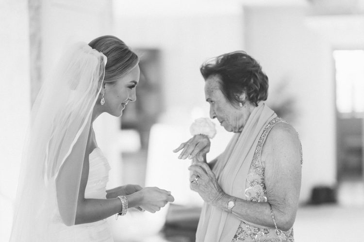 Bride and her grandmother smell her corsage on the morning of her Mallard Island Yacht Club wedding. Captured by NJ wedding photographer Ben Lau.