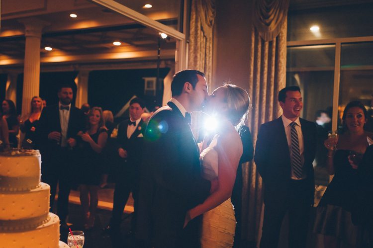 Couples kiss after the cake cutting during their Mallard Island Yacht Club wedding reception. Captured by NJ wedding photographer Ben Lau.