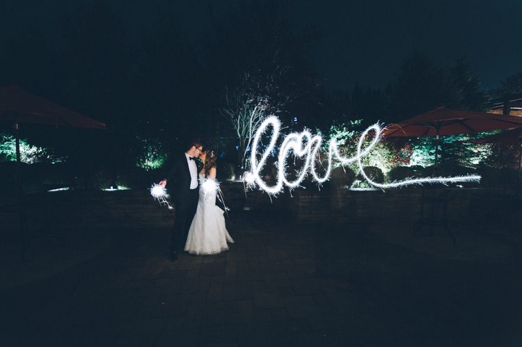 Bride and groom spells "love" with sparklers during a wedding at the Stone House in Stirling Ridge. Captured by NJ wedding photographer Ben Lau.