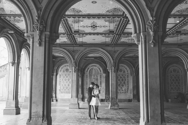 Couple share a kiss in the Bethesda Arcade during their engagement session in Central Park. Captured by NYC wedding photographer Ben Lau.