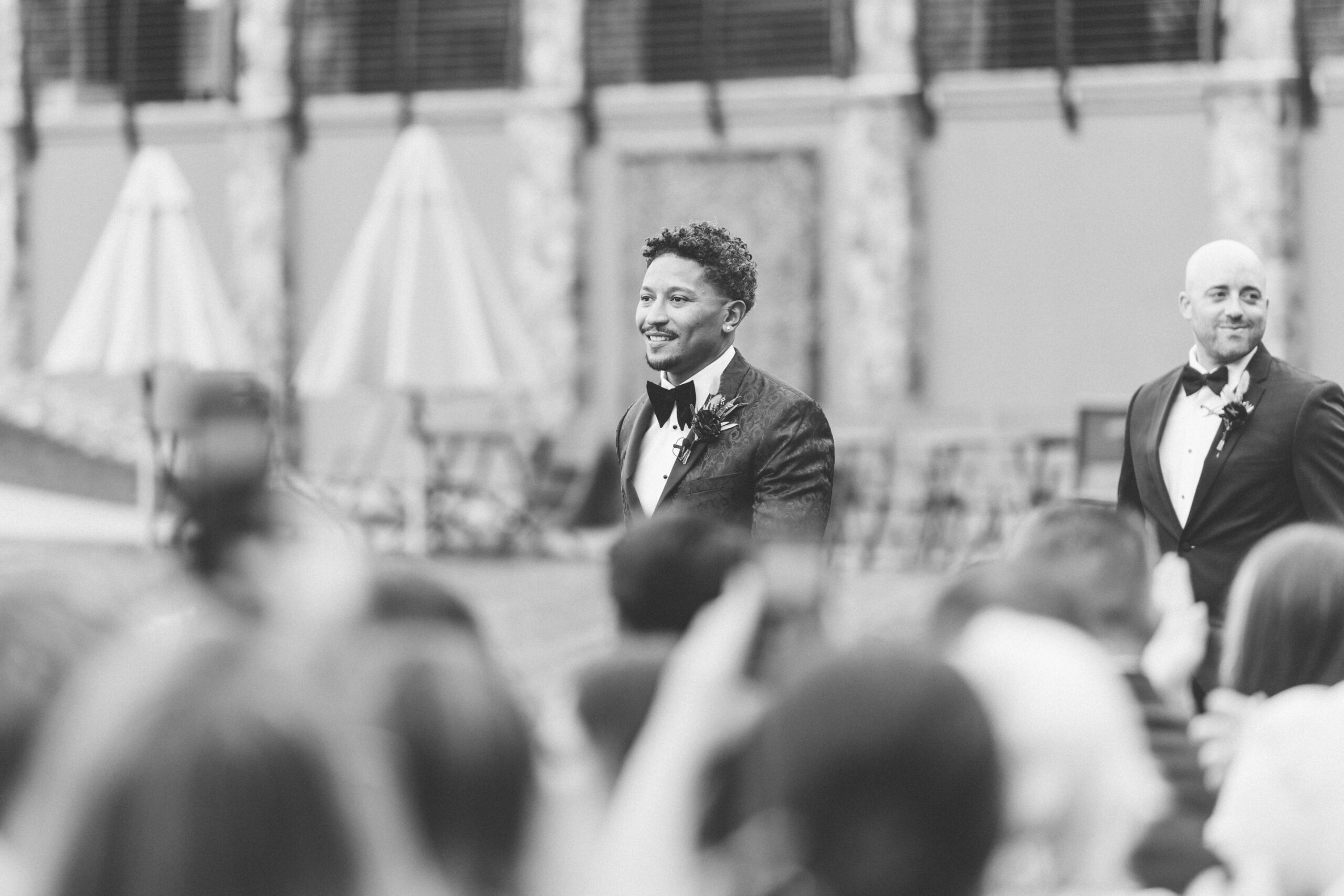 Black and white view of the ceremony processional with Brandon waiting near the aisle.