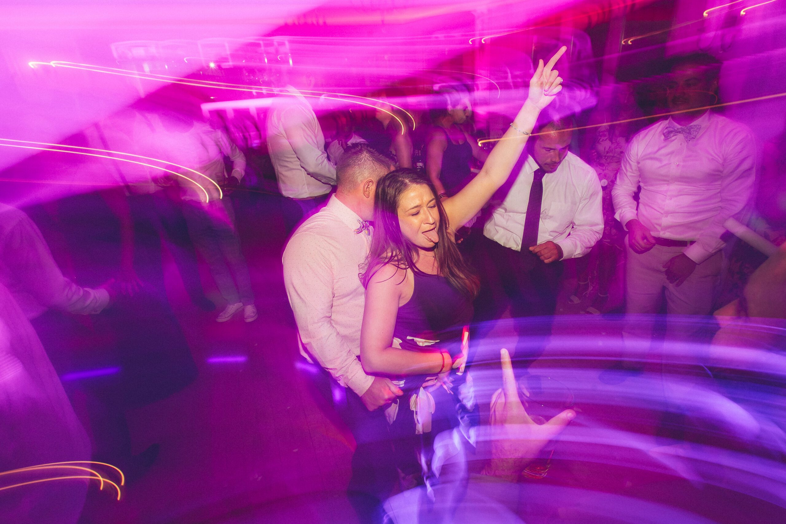 Alliee dancing in bright magenta light during the late-night reception party.